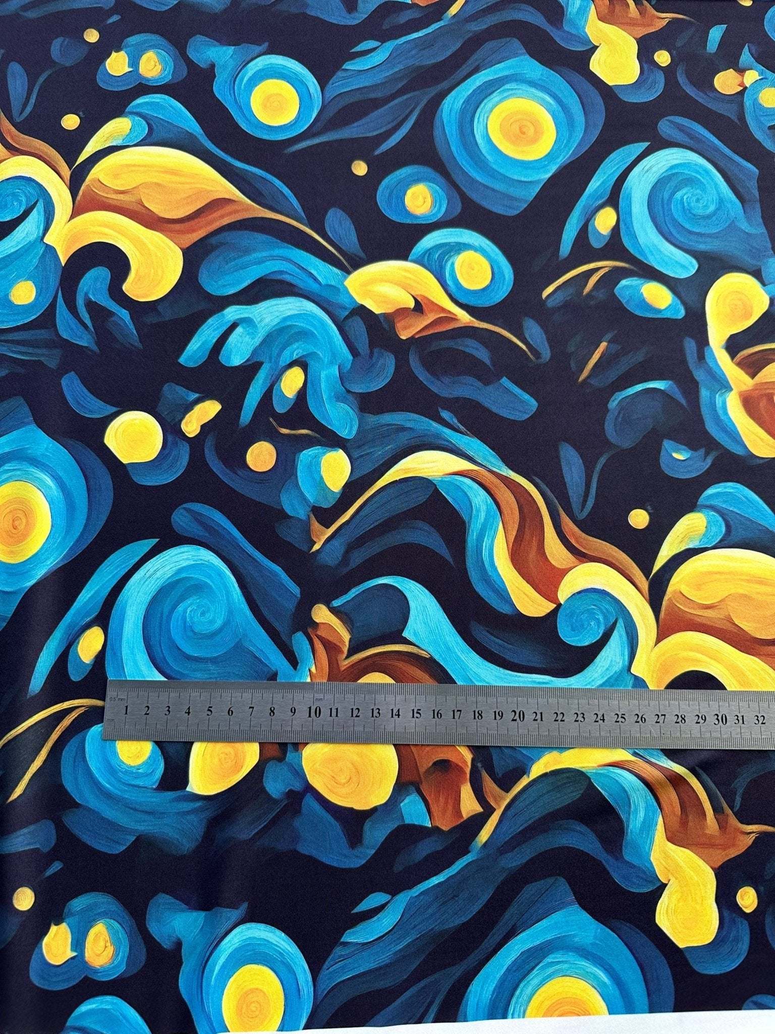 Blue and yellow Van Gogh style spandex fabric with swirling patterns and measuring ruler for scale