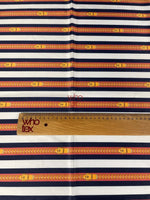 Striped fabric with nautical-inspired belt and chain print in navy, white, and yellow tones with a wooden ruler for scale