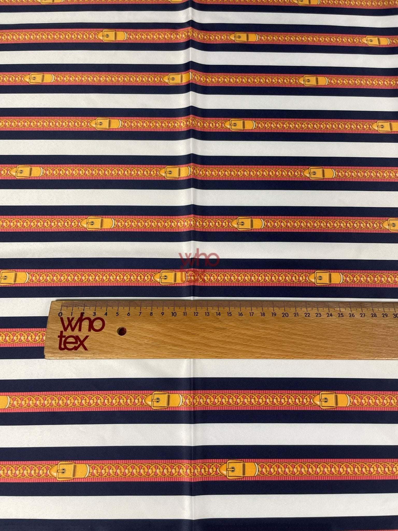 Striped fabric with nautical-inspired belt and chain print in navy, white, and yellow tones with a wooden ruler for scale