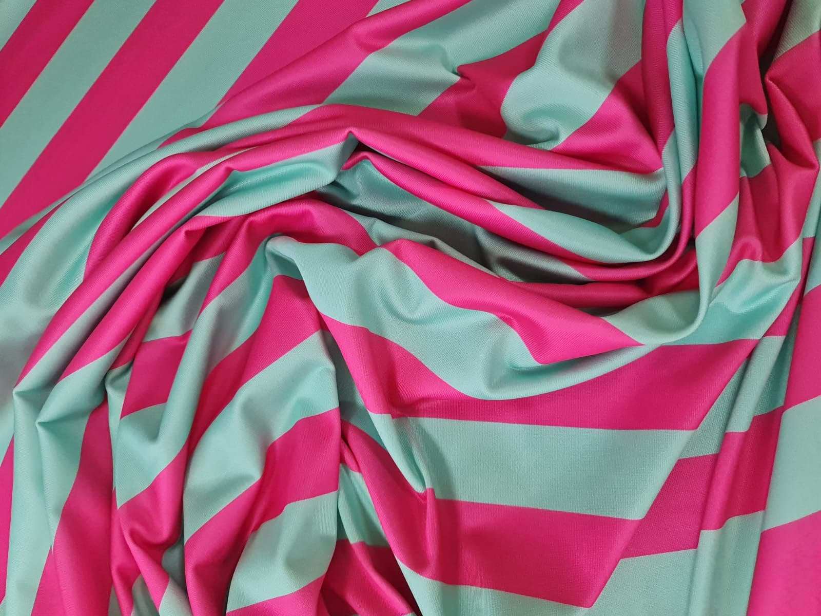 Mint green and pink striped fabric with wide horizontal stripes, draped and folded, ideal for sewing and crafting projects