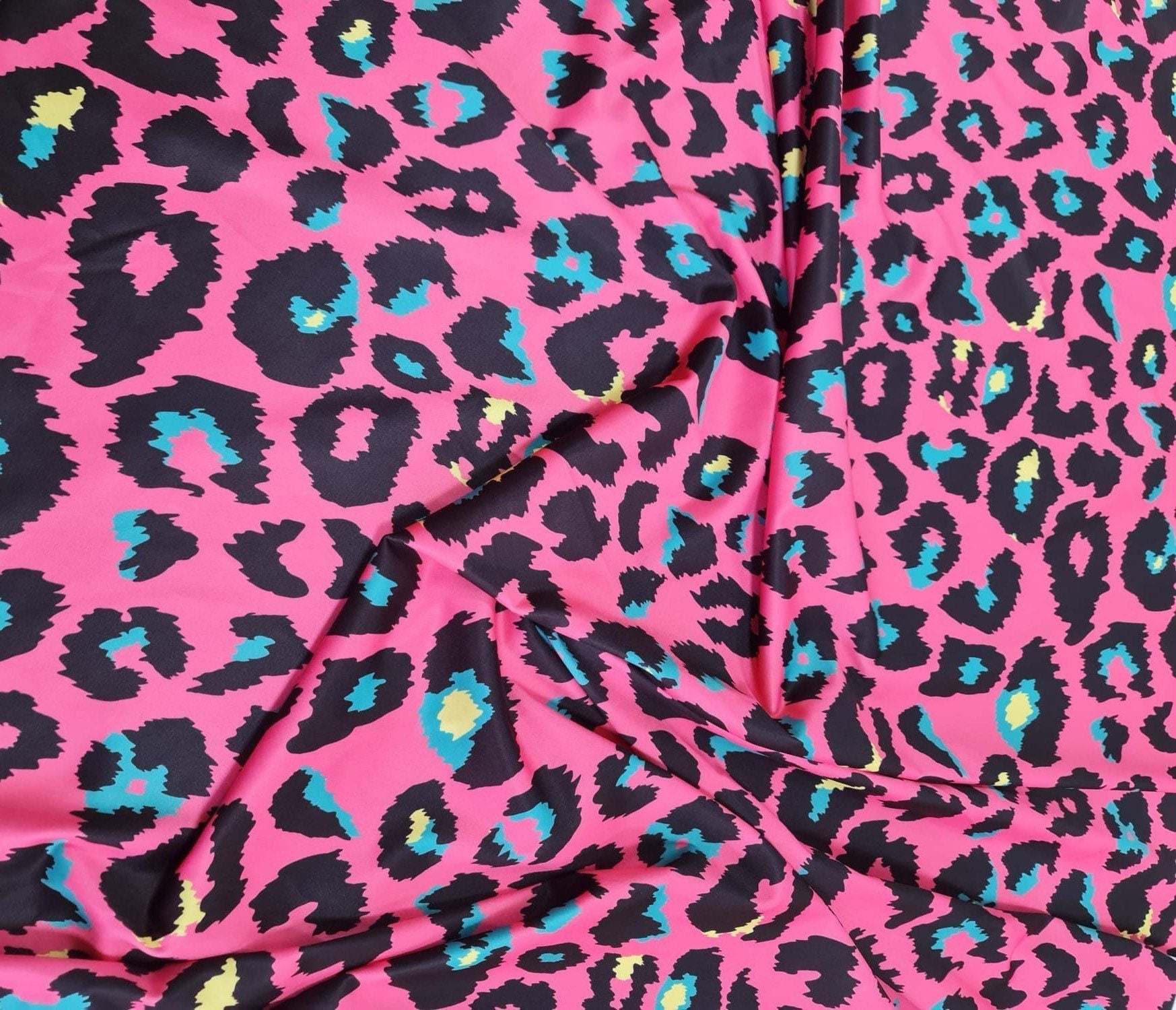 Sugar pink leopard print fabric with black spots and blue and yellow accents, 150cm wide textile for clothing and crafts.