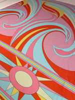 Retro psychedelic swirl and sun print fabric in pink, red, blue, and yellow colors with vibrant retro patterns.