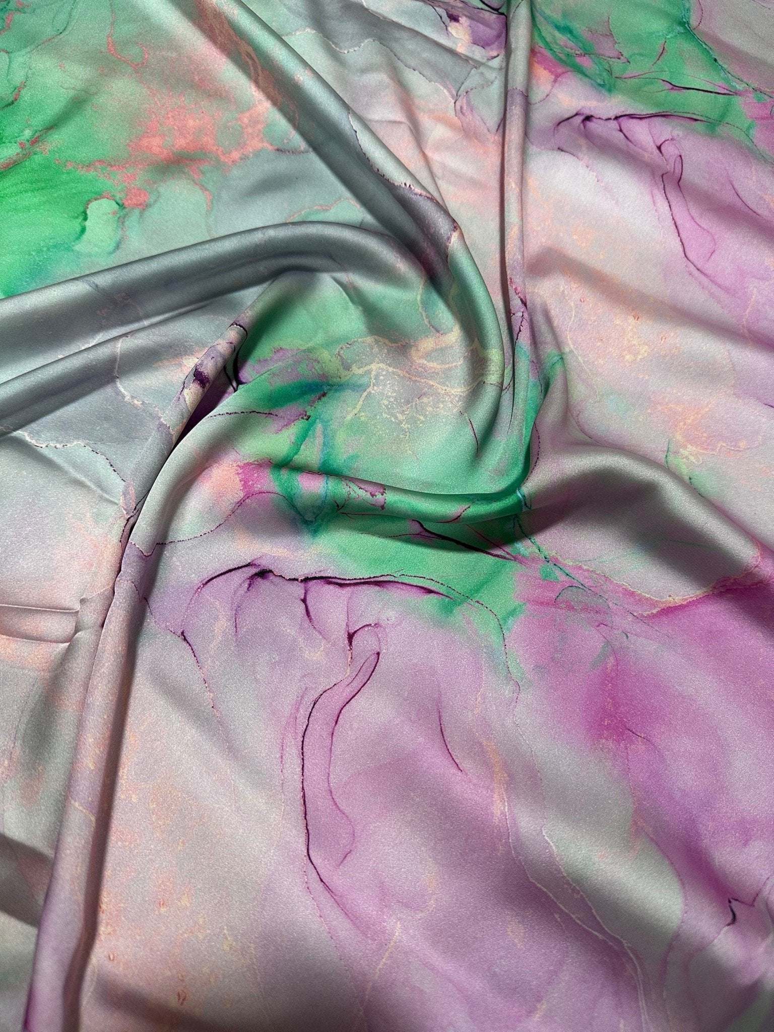 Abstract watercolor print fabric with soft green, pink, and purple tie-dye patterns and a smooth texture