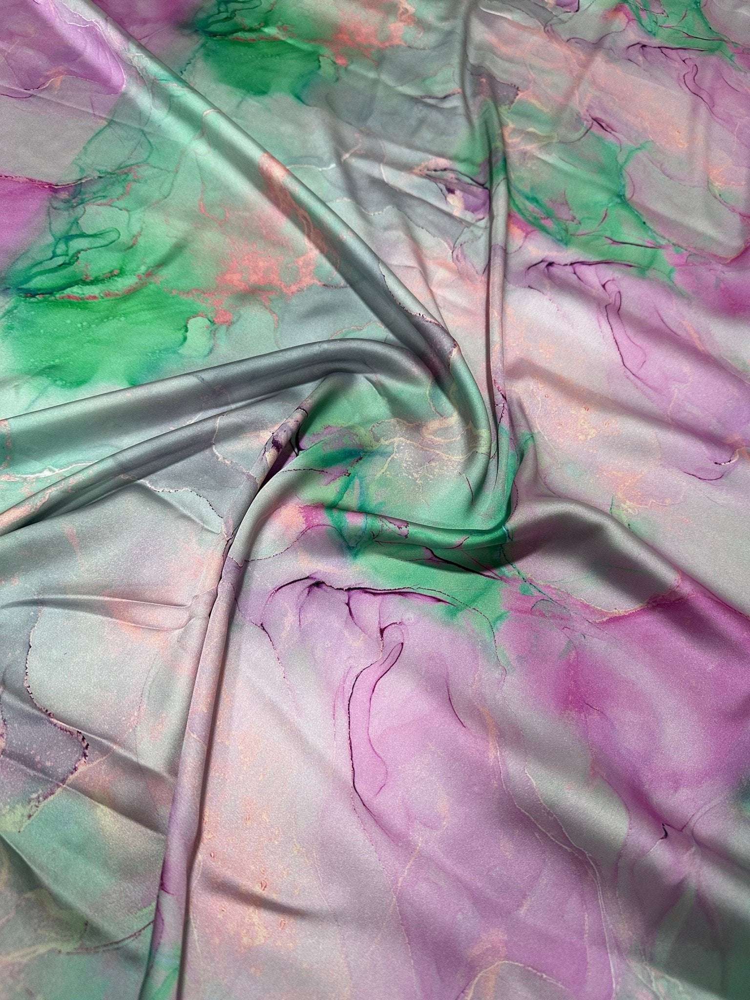 Abstract watercolor print fabric with soft green, pink, and purple tie-dye design perfect for sewing and crafts