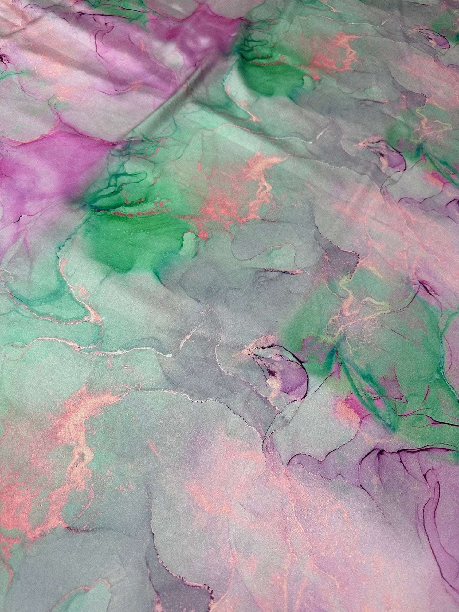 Abstract watercolor print fabric with pink, green, and purple tie-dye design, ideal for sewing and crafts