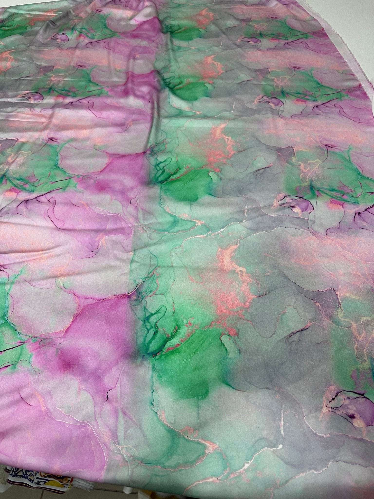 Abstract watercolor print fabric in soft pink, green, and gray tie-dye patterns for sewing and crafts