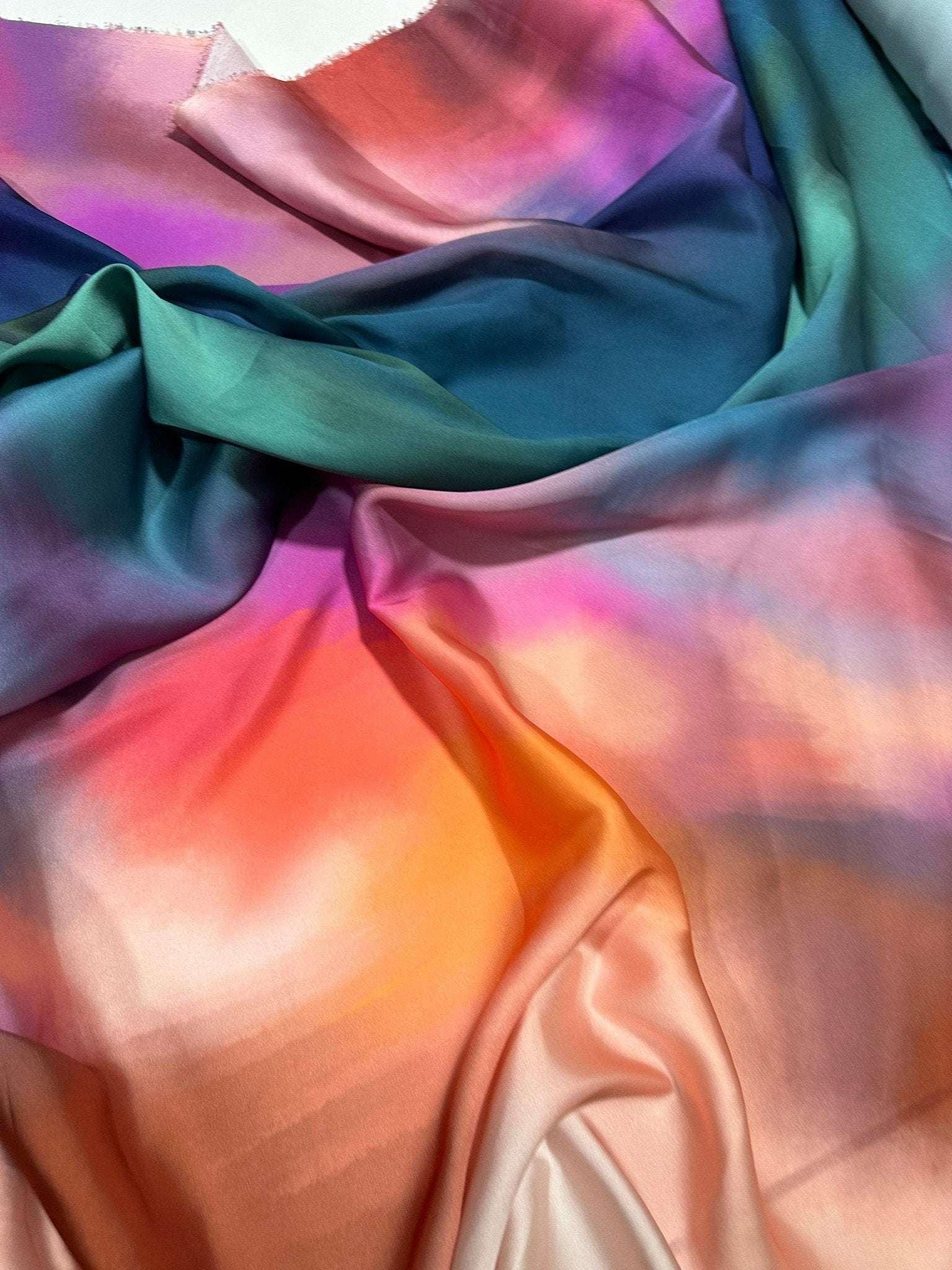 Rainbow multicolor satin fabric with smooth, vibrant gradient colors and a glossy finish ideal for sewing and crafting projects