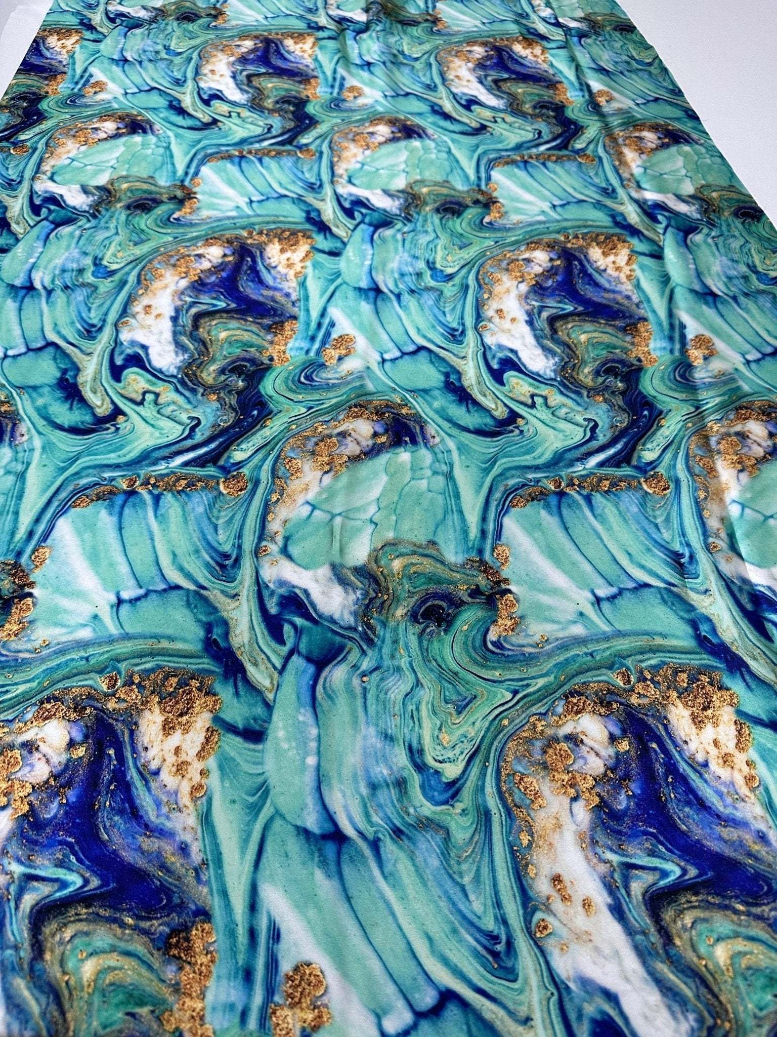 Turquoise and blue marble print fabric with swirling patterns and gold accents, 150cm wide