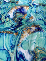Close-up of turquoise and blue marble print fabric with gold accents and swirling patterns
