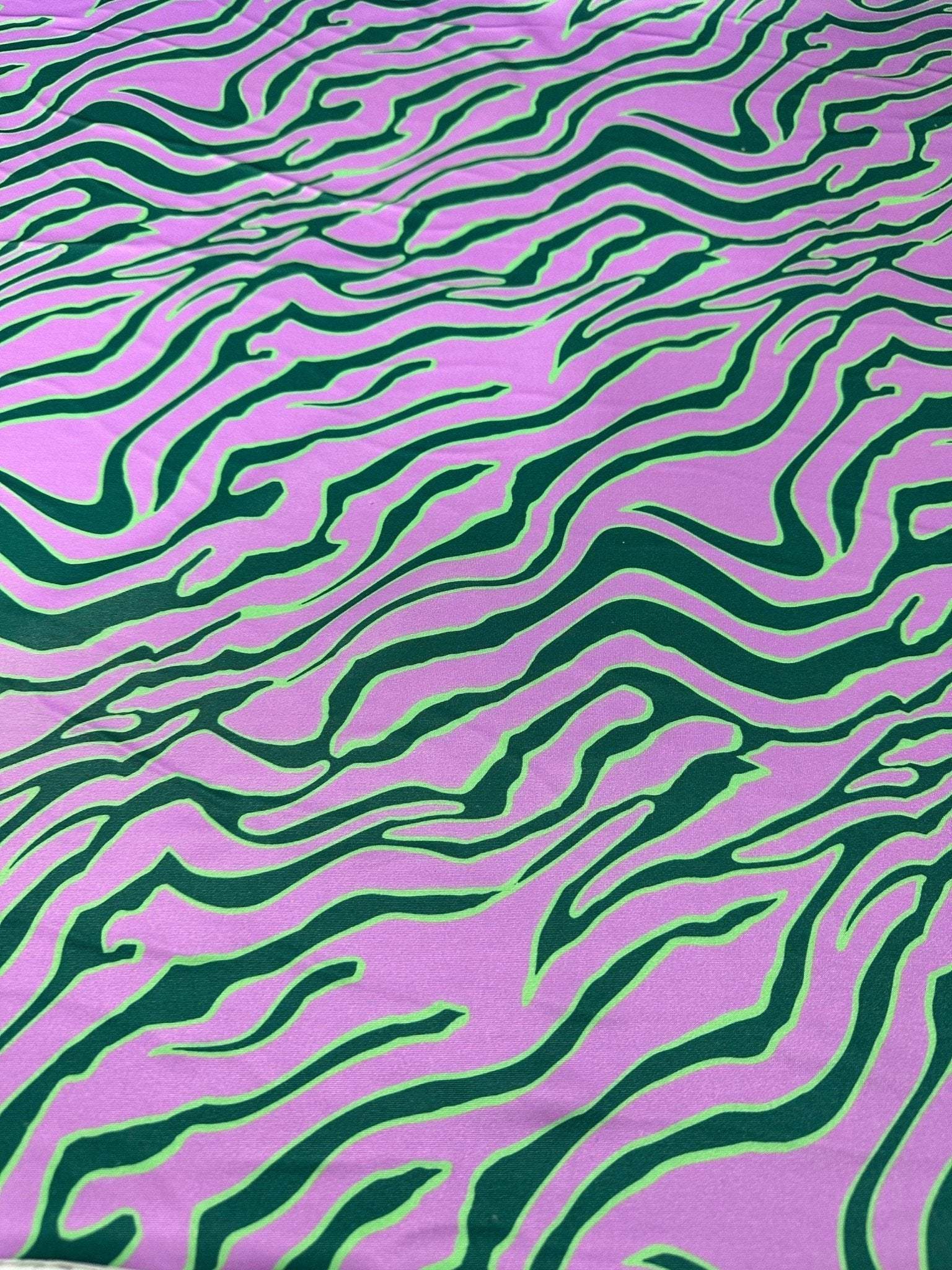 Exotic tiger pattern fabric in vibrant green and purple with bold animal print design