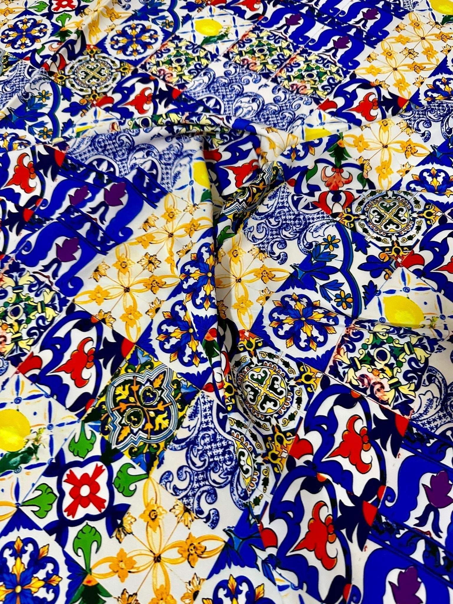 Colorful tile pattern fabric with intricate blue, yellow, red, and green designs on white background, ideal for sewing and crafting projects