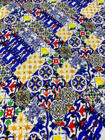 Close-up of colorful tile pattern fabric with blue, yellow, red, and green designs on white background