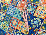 Colorful tile pattern fabric with pink scissors on top for sewing projects