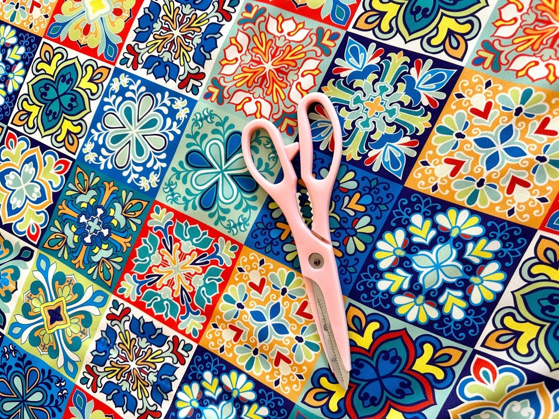 Colorful tile pattern fabric with pink scissors on top for sewing projects