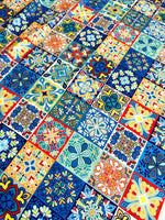 Colorful tile pattern fabric with blue, orange, and yellow intricate designs, ideal for sewing projects and home decor.