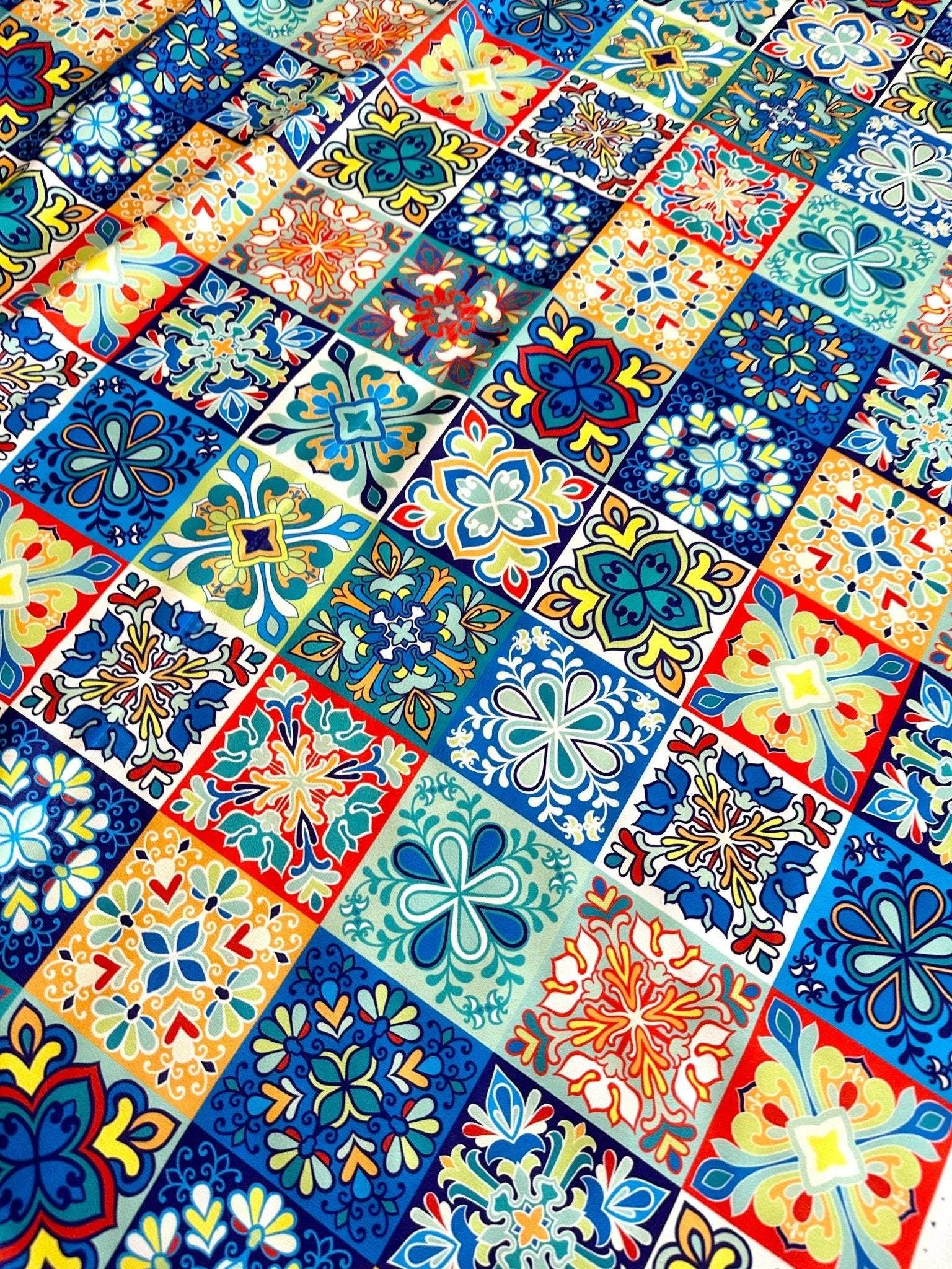 Colorful tile pattern fabric with blue, orange, and yellow intricate designs, ideal for sewing projects and home decor.