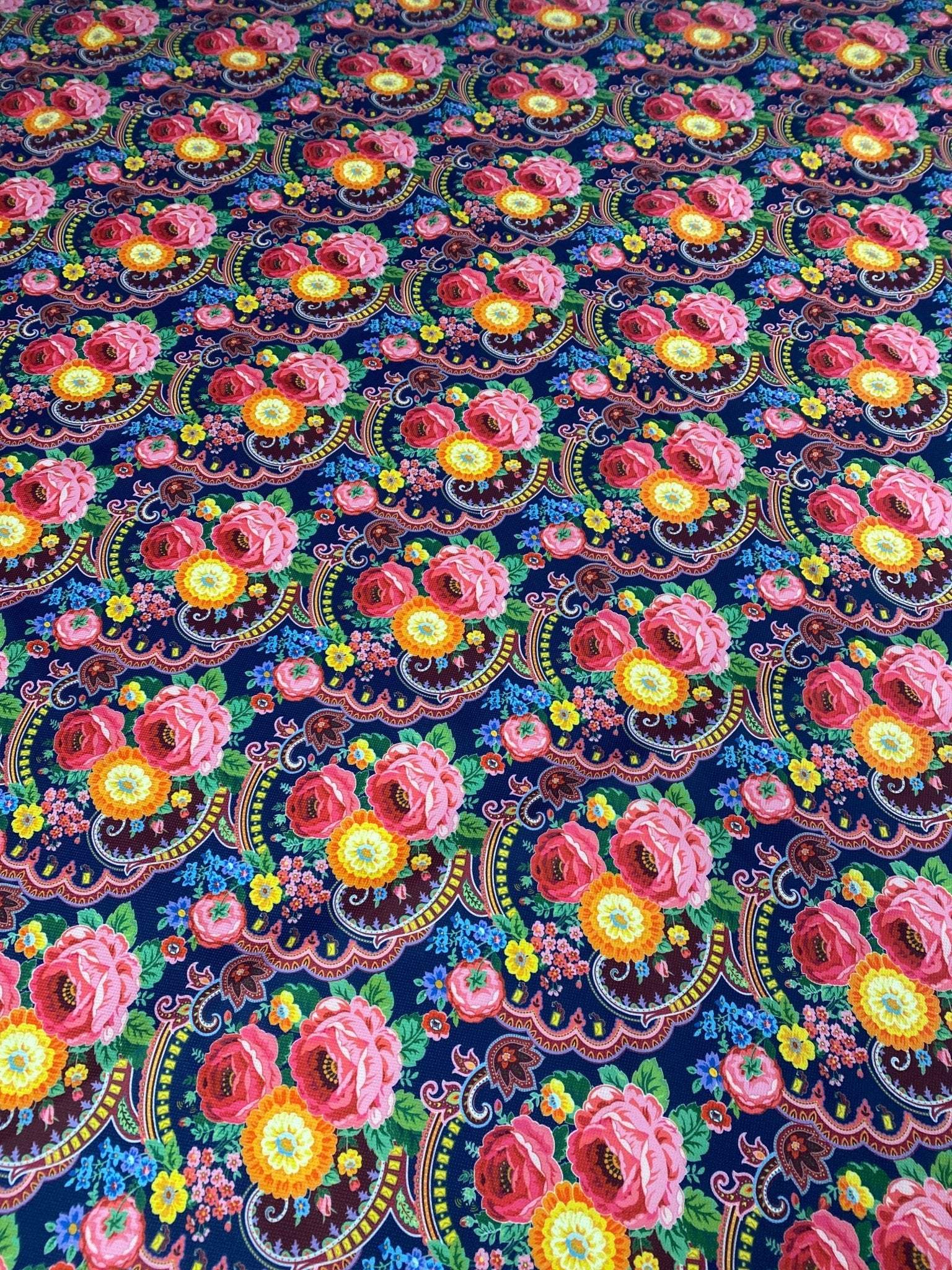 Close-up of vibrant tiny floral design upholstery fabric with pink and yellow flowers on a dark blue background