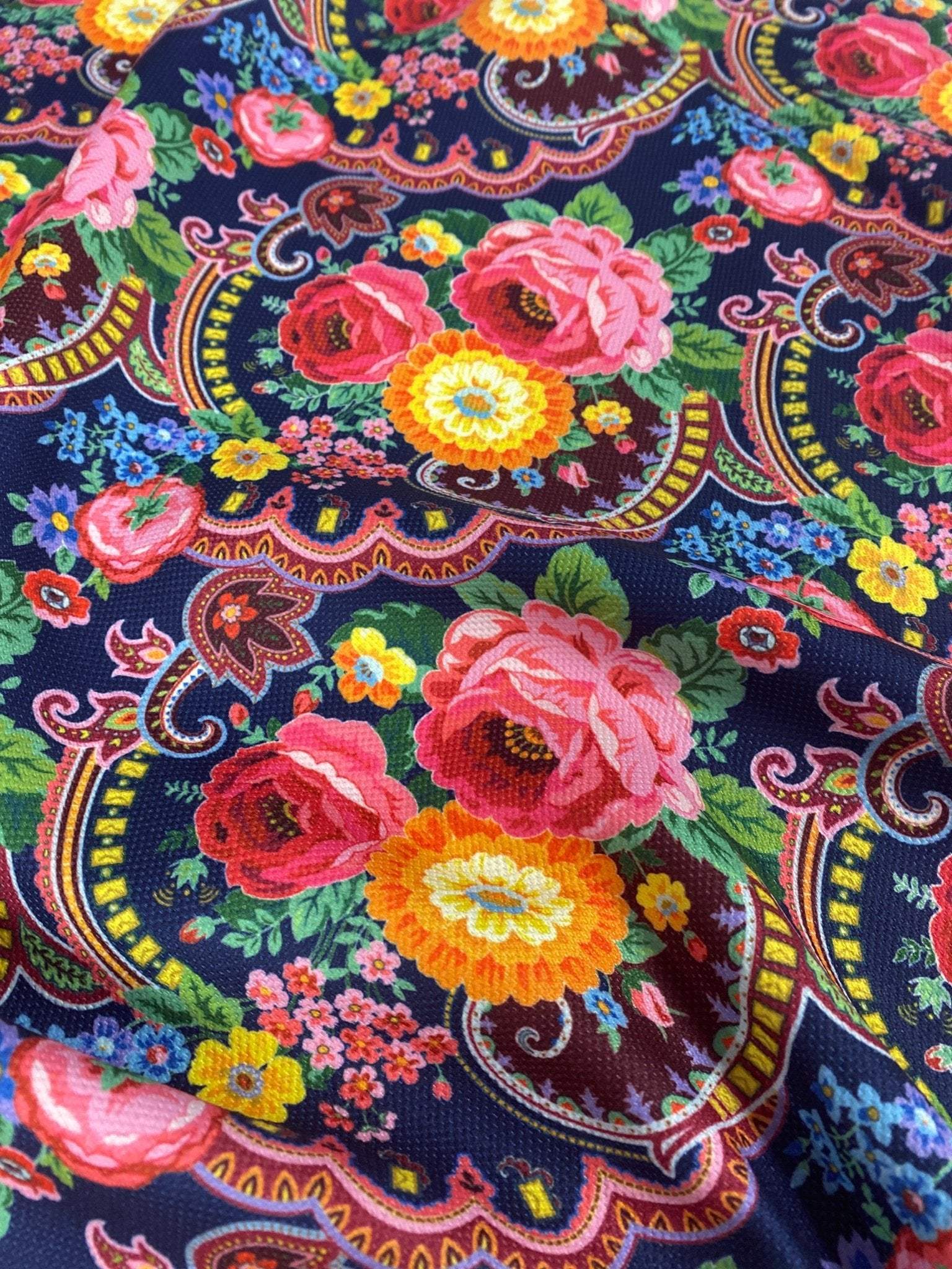 close-up of tiny floral design upholstery fabric with vibrant pink, yellow, and blue flowers on a dark background