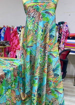 Fabric bundle with tropical leaves and leopard patterns in vibrant colors on a turquoise background displayed on a dress form in a fabric store.