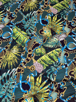 Tropical fabric with vibrant chain belt pattern featuring blue and gold chains over green tropical leaves design