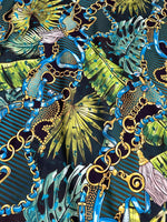 Tropical fabric with vibrant chain belt pattern featuring blue, gold chains and green tropical leaves on dark background
