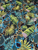 Tropical fabric with vibrant chain belt pattern featuring blue chains, gold details, and green tropical leaves on dark background
