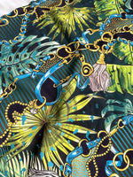 Tropical fabric with vibrant chain belt pattern featuring blue belts, gold chains, and green tropical leaves on dark background