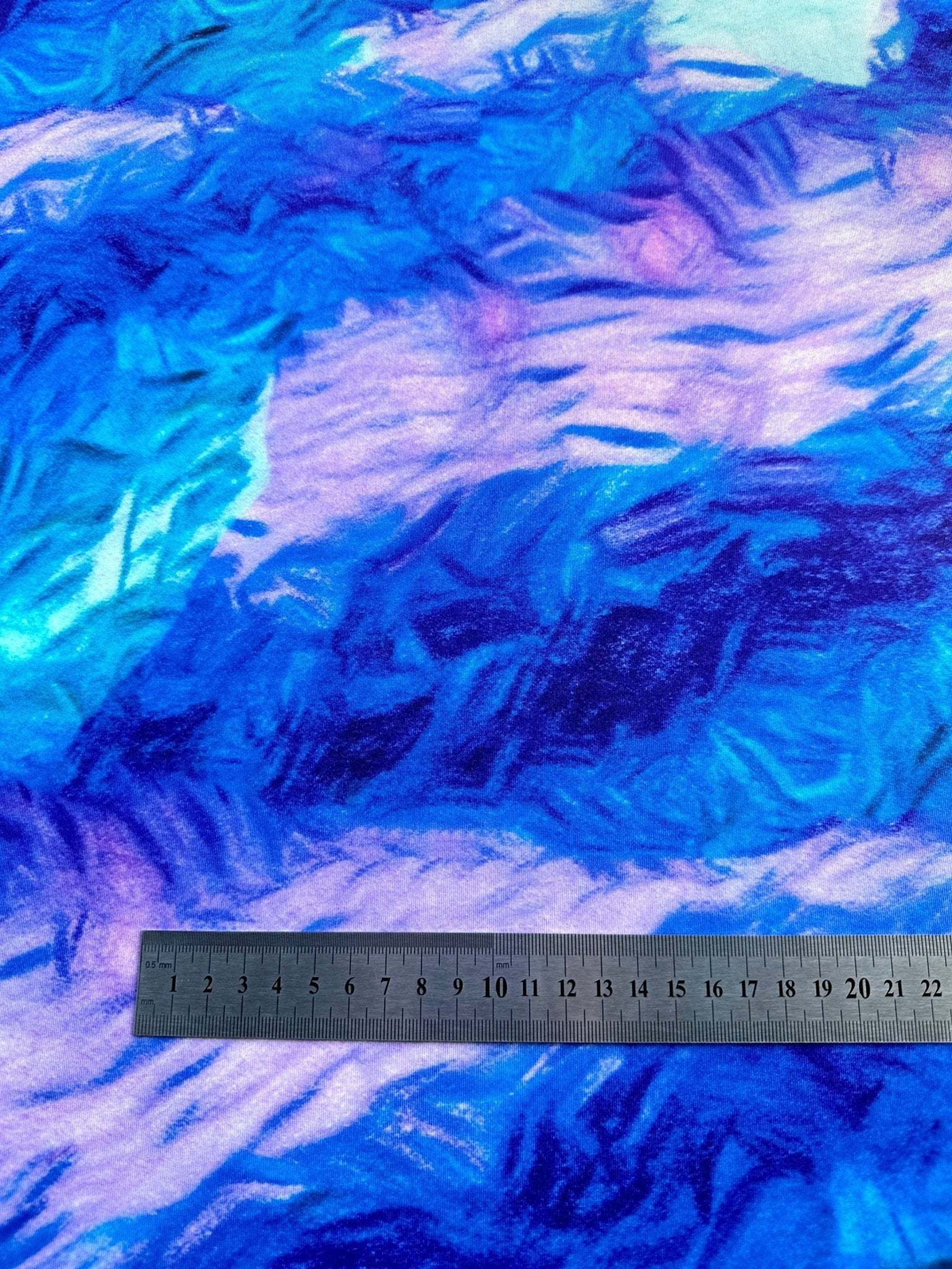 Close-up of abstract blue and purple tie dye pattern fabric with ruler for scale