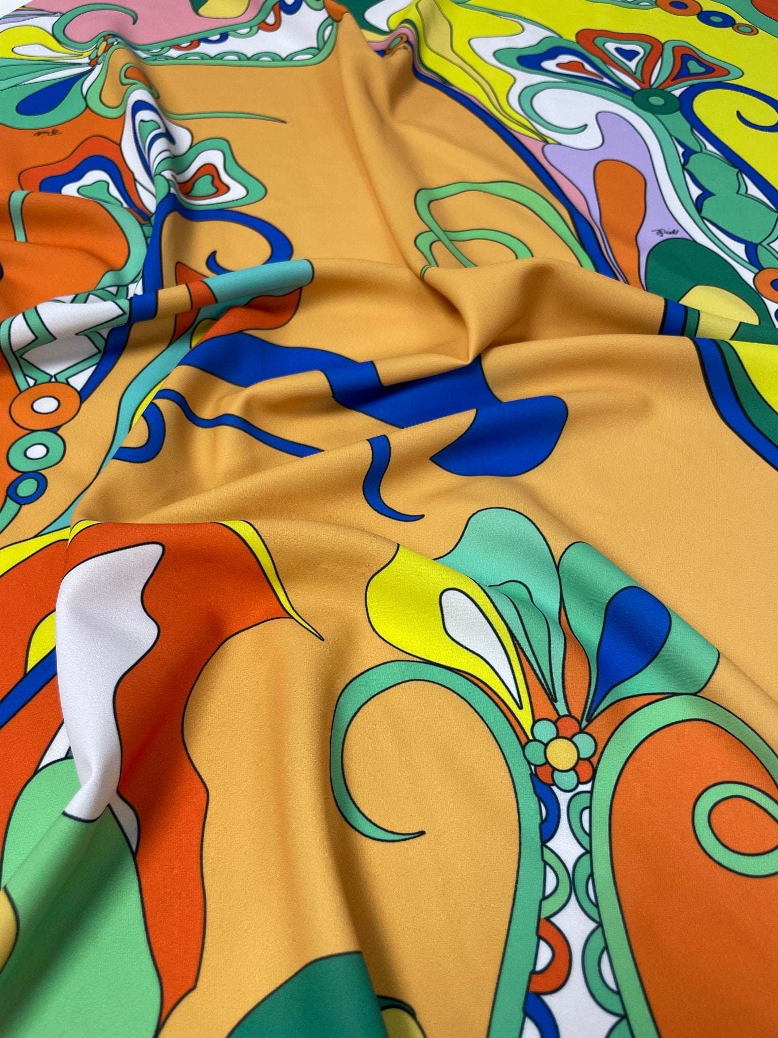 Close-up of vibrant psychedelic pattern fabric with bold colorful abstract designs and soft texture
