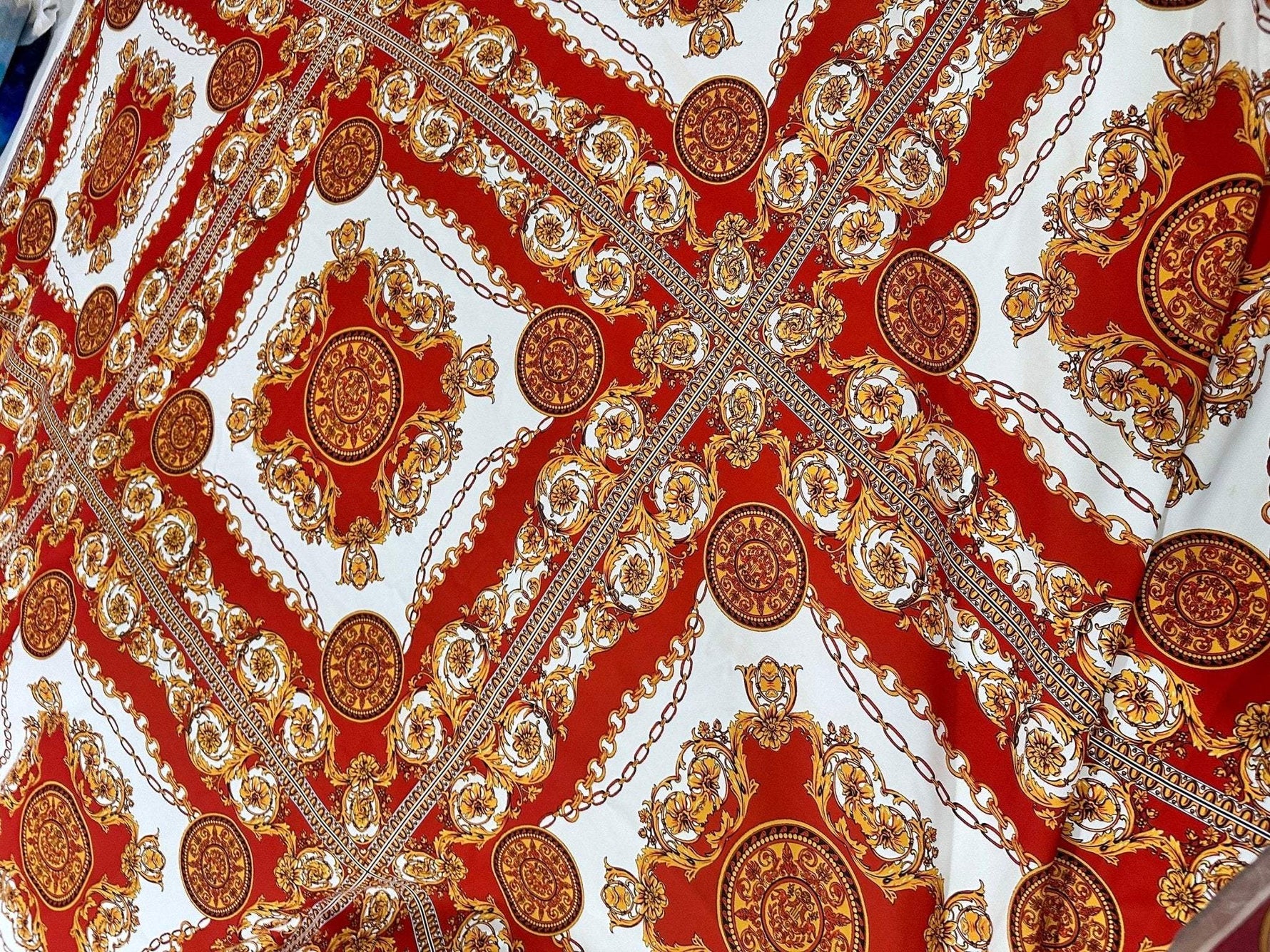 Vintage Baroque pattern fabric with intricate gold and red ornate design on white background, ideal for upholstery and decor projects.