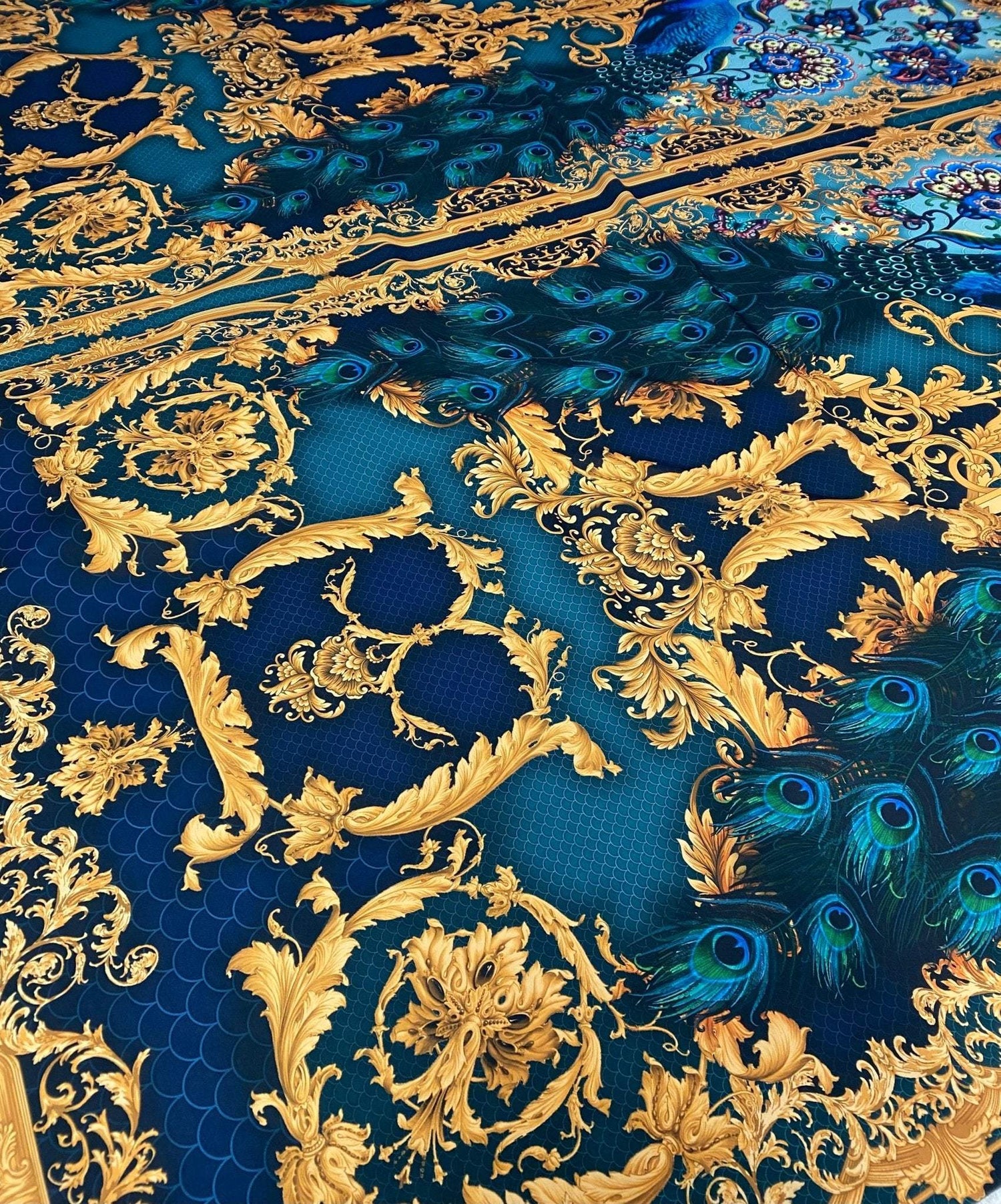 Vintage peacock pattern fabric with intricate gold and blue designs and vibrant peacock feathers.