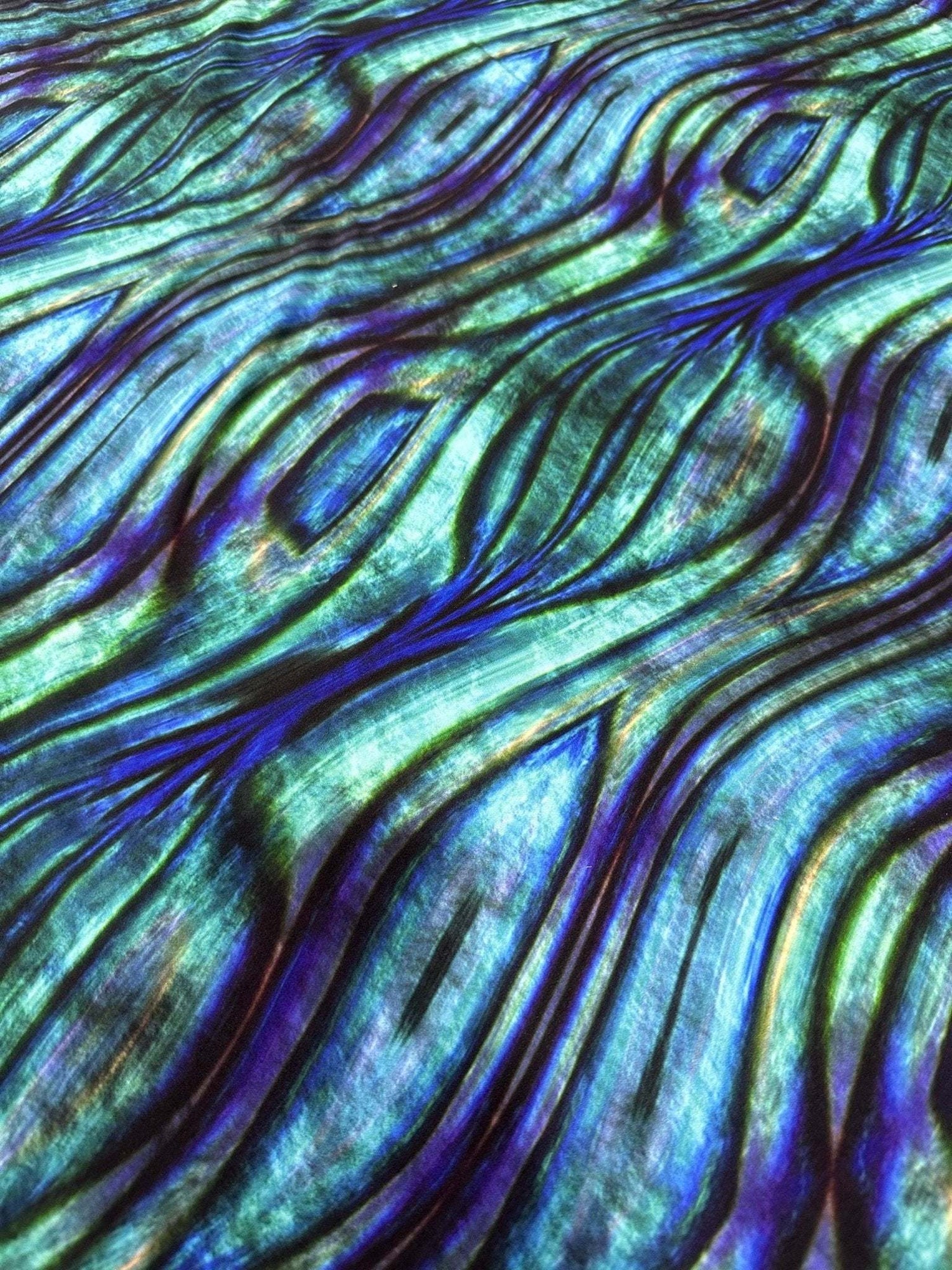 Close-up of iridescent wave pattern fabric with blue and green hues and textured design
