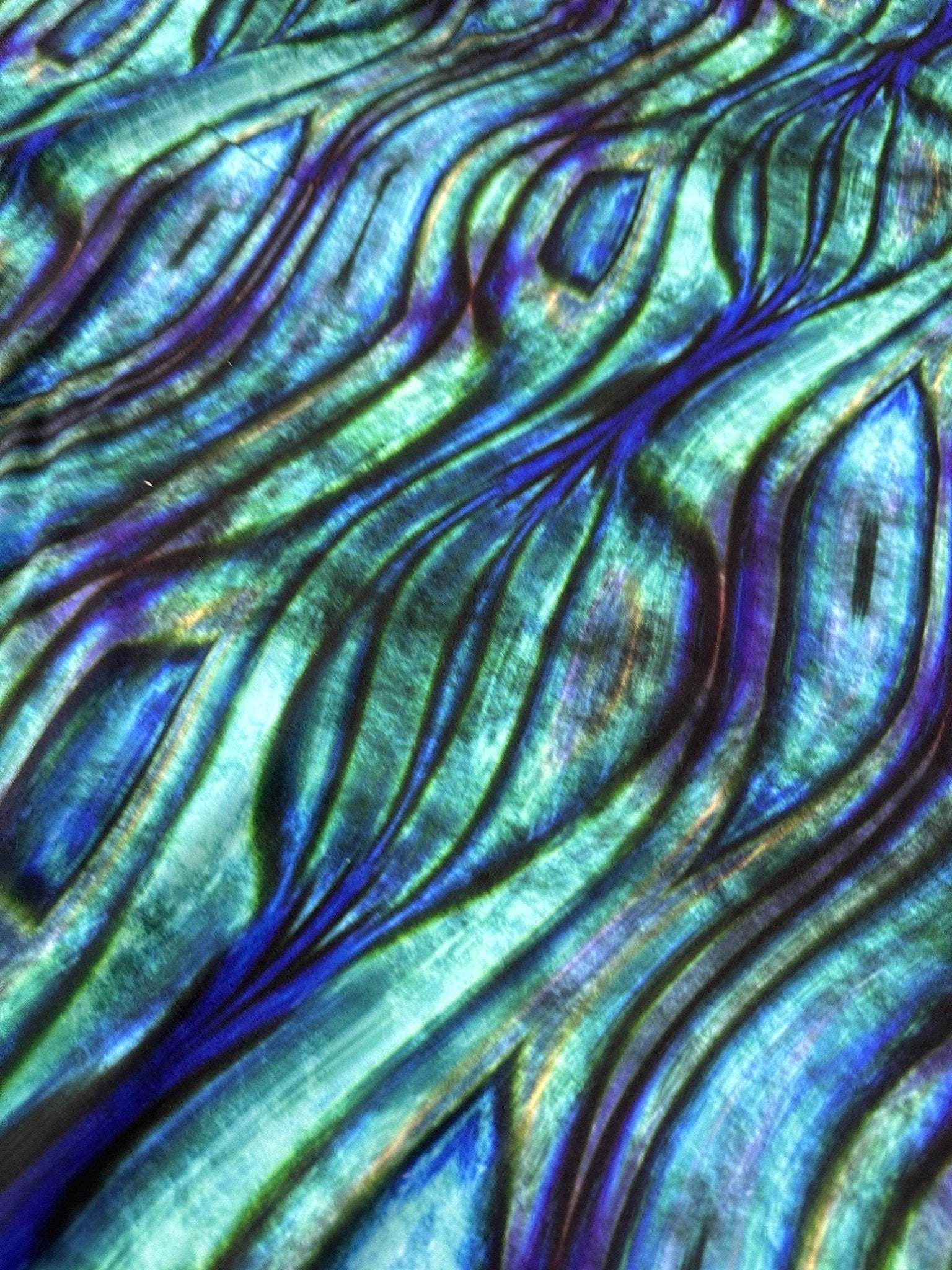 Close-up of blue and green wave pattern fabric with textured design and iridescent sheen