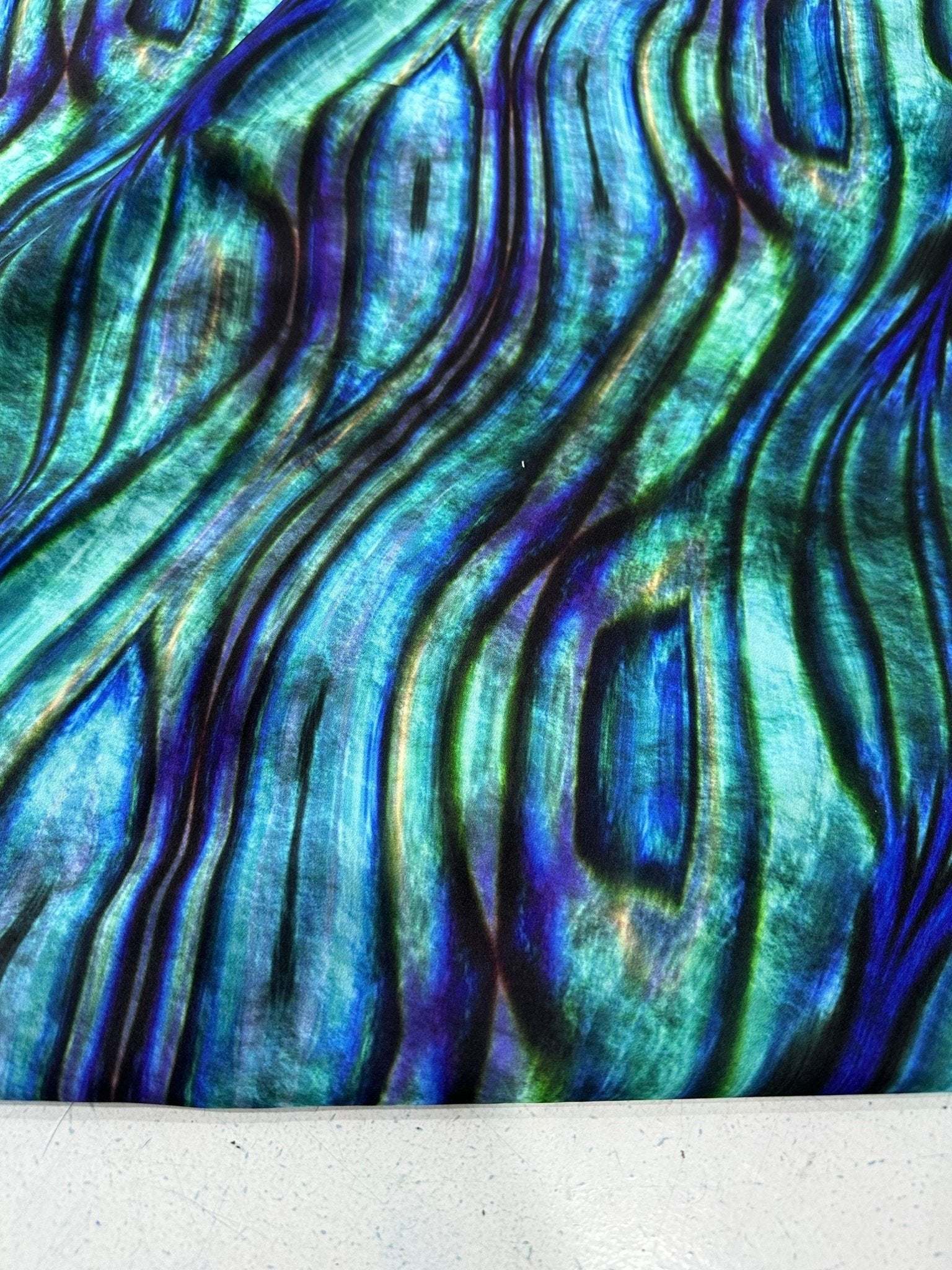 Close-up of iridescent wave pattern fabric in blue and green hues with textured design