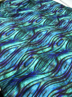 Close-up of blue and green wave pattern fabric with textured design and 150cm width