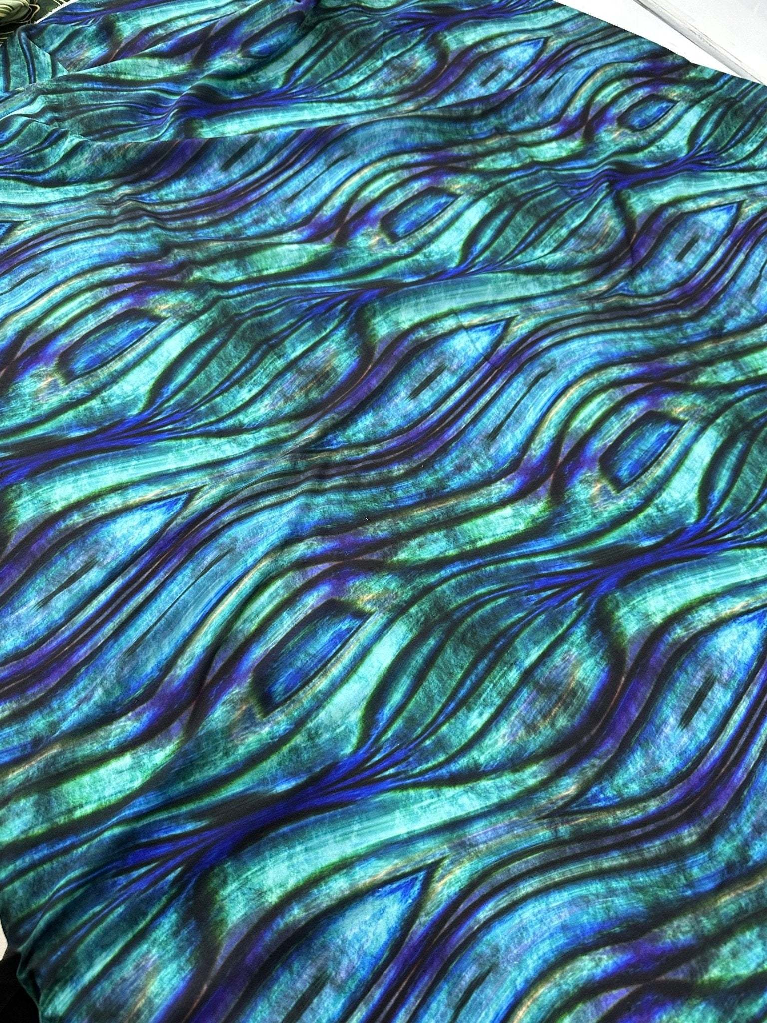 Close-up of blue and green wave pattern fabric with textured design and 150cm width