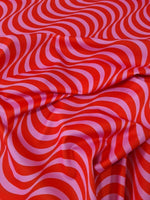 Red and pink striped wave pattern fabric with vibrant decorative design, ideal for sewing and crafting projects