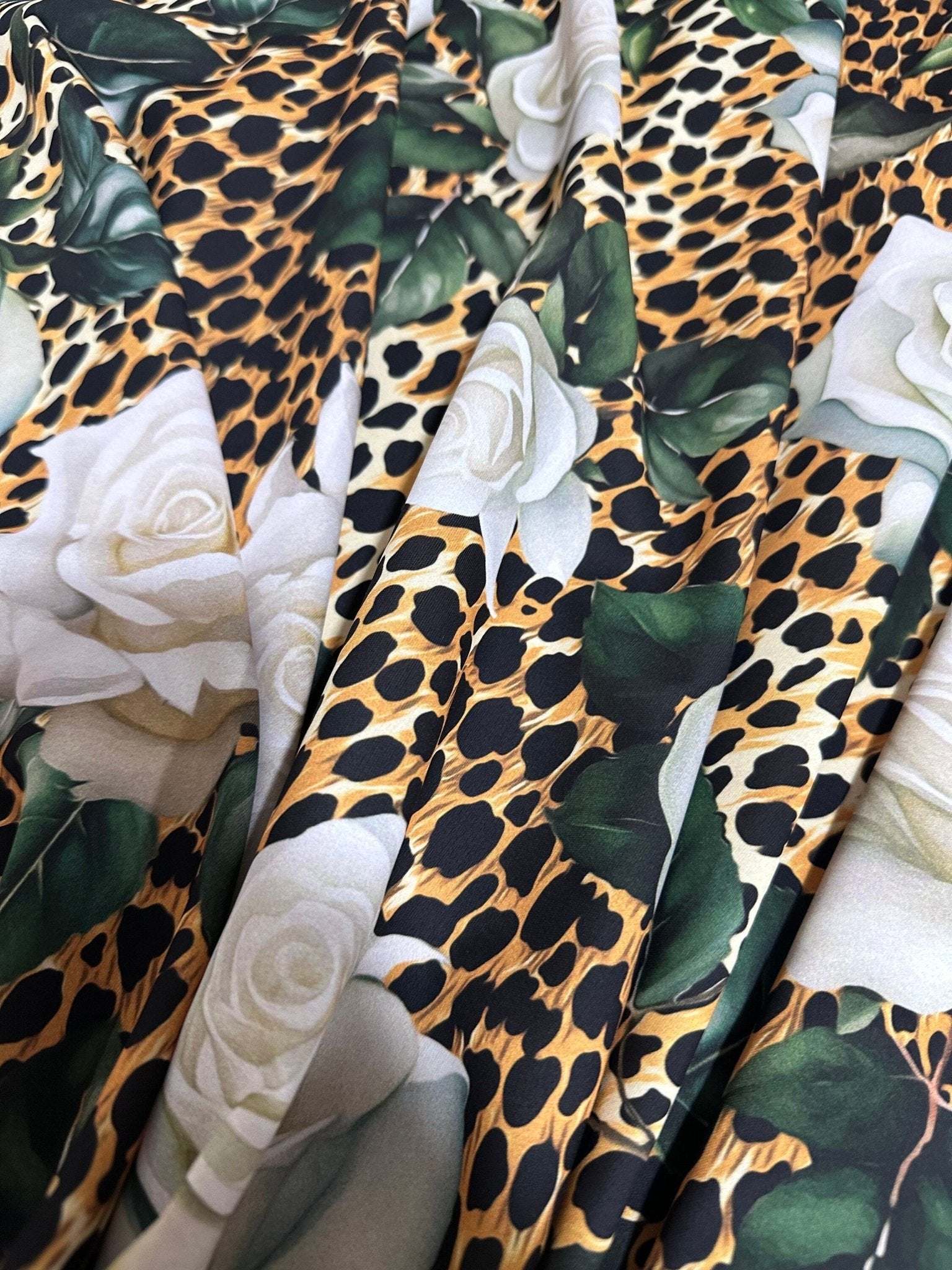 Floral and cheetah pattern fabric with white roses and green leaves on animal print background