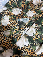 Floral and cheetah pattern fabric with white roses and green leaves on cheetah print background