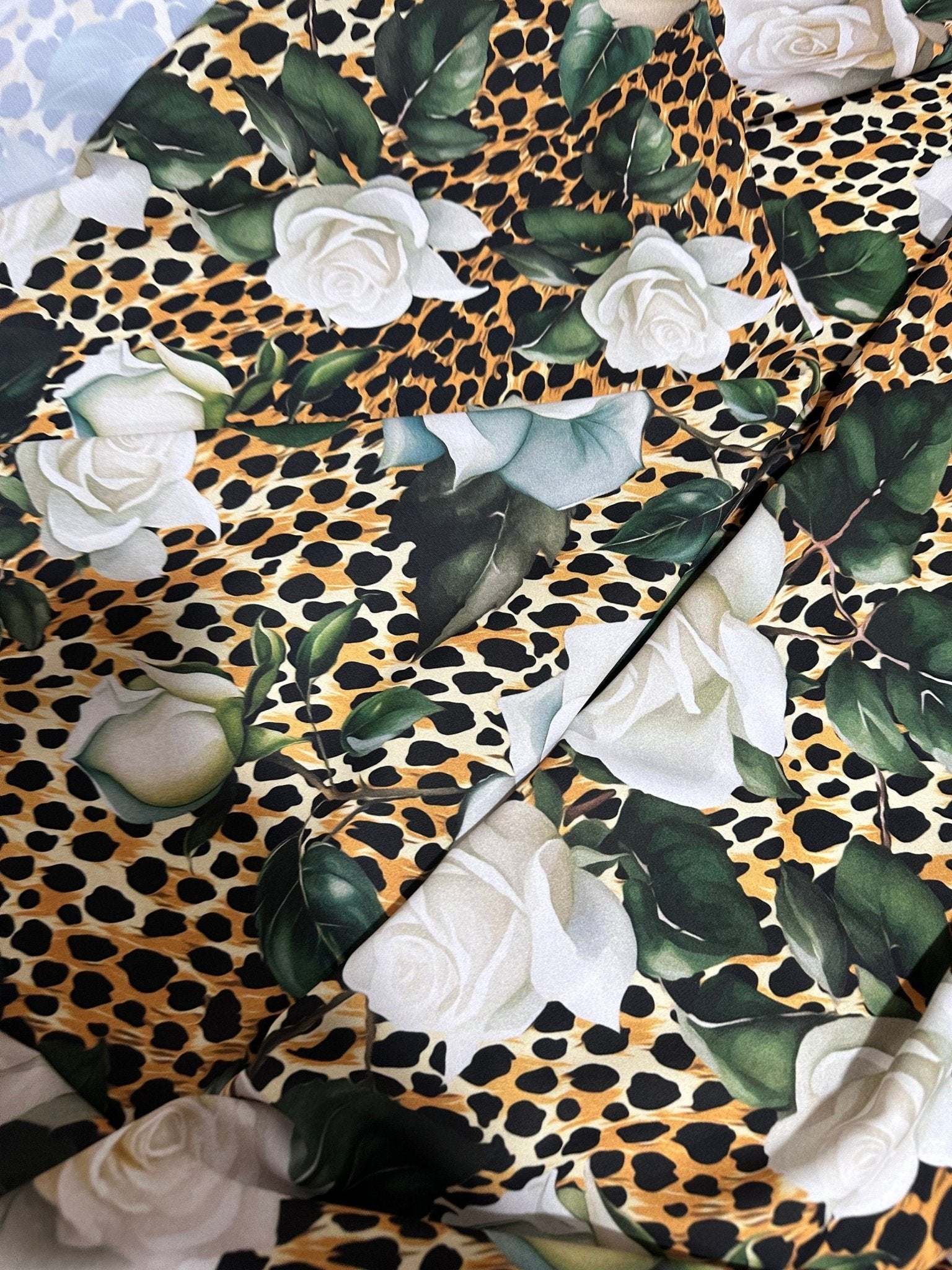 Floral and cheetah pattern fabric with white roses and green leaves on cheetah print background