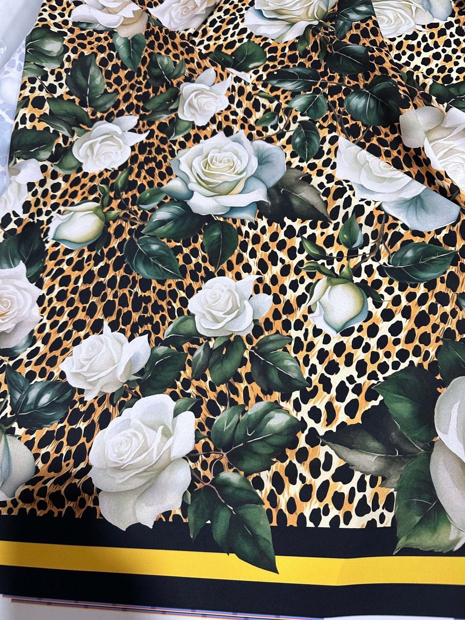 Floral and cheetah pattern fabric featuring white roses and green leaves on a cheetah print background with black and yellow border