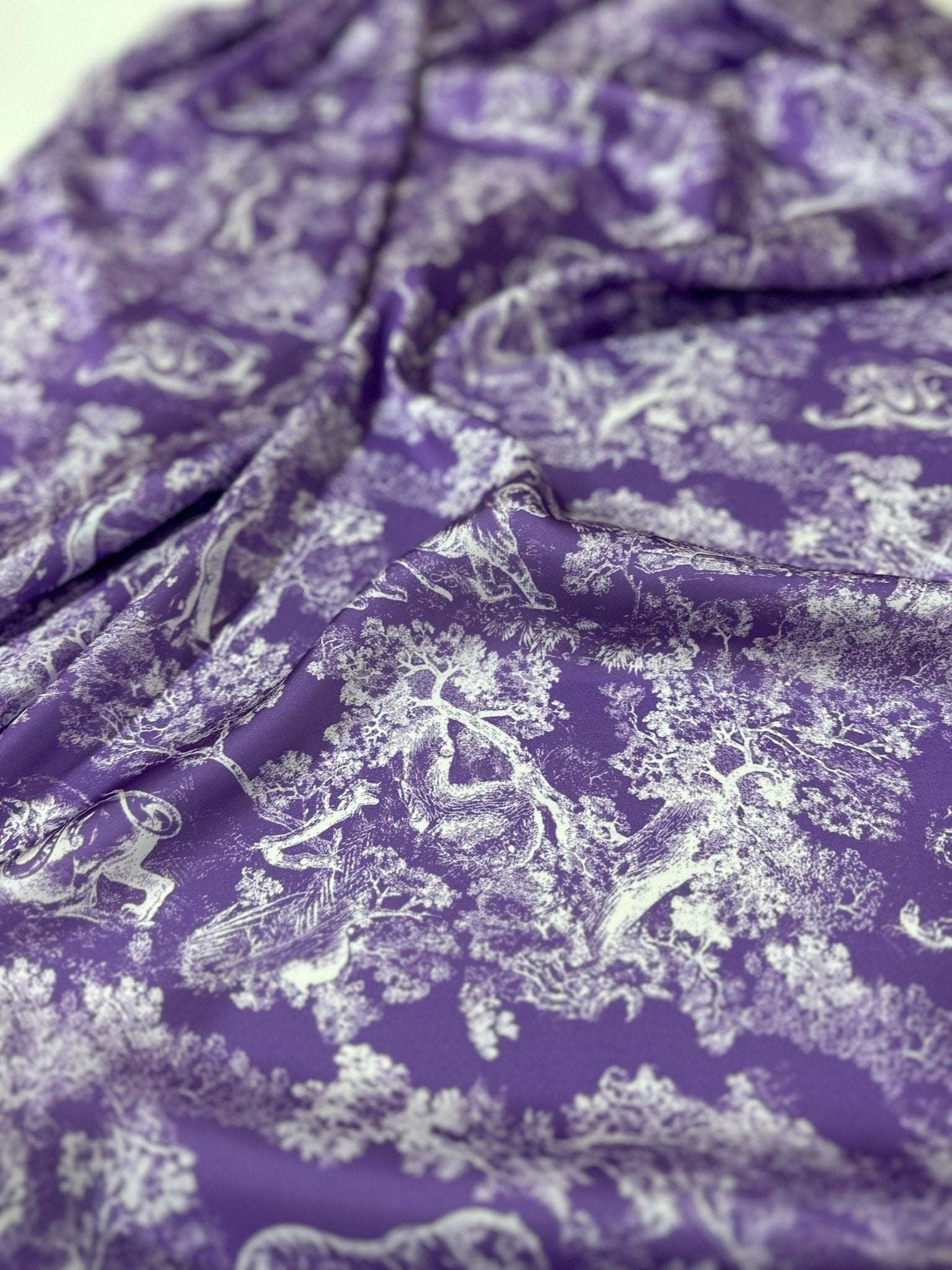 Purple fabric with white wild forest animal pattern, 150cm wide, ideal for upholstery, crafts, and apparel projects.