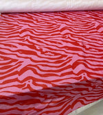 Close-up of zebra pattern 4-way stretch spandex lurex fabric in red and pink with a smooth satin finish for fashion and crafts