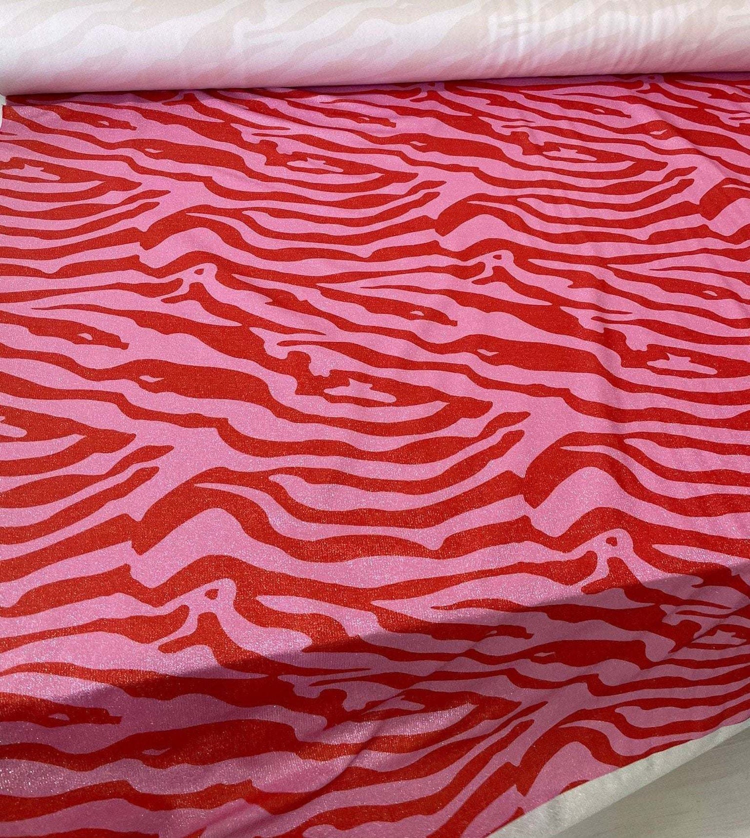 Close-up of zebra pattern 4-way stretch spandex lurex fabric in red and pink with a smooth satin finish for fashion and crafts