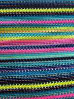 Colorful zigzag knit jersey fabric with vibrant stripes in black, yellow, pink, and blue, ideal for fashion garments
