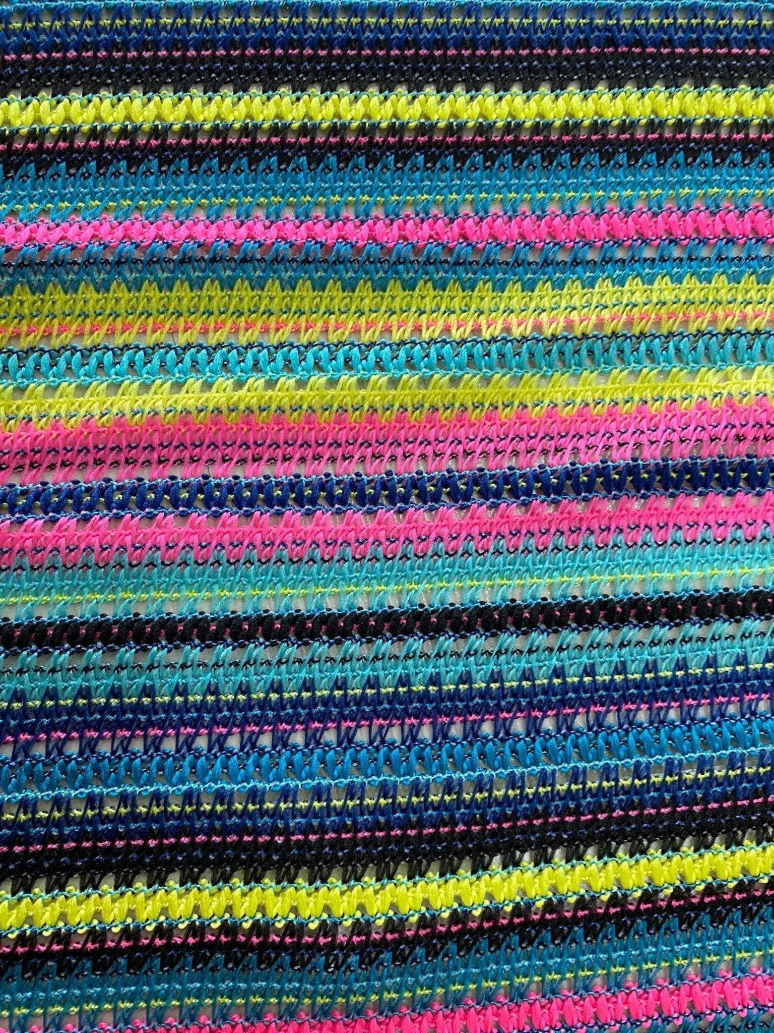 Colorful zigzag knit jersey fabric with vibrant stripes in black, yellow, pink, and blue, ideal for fashion garments