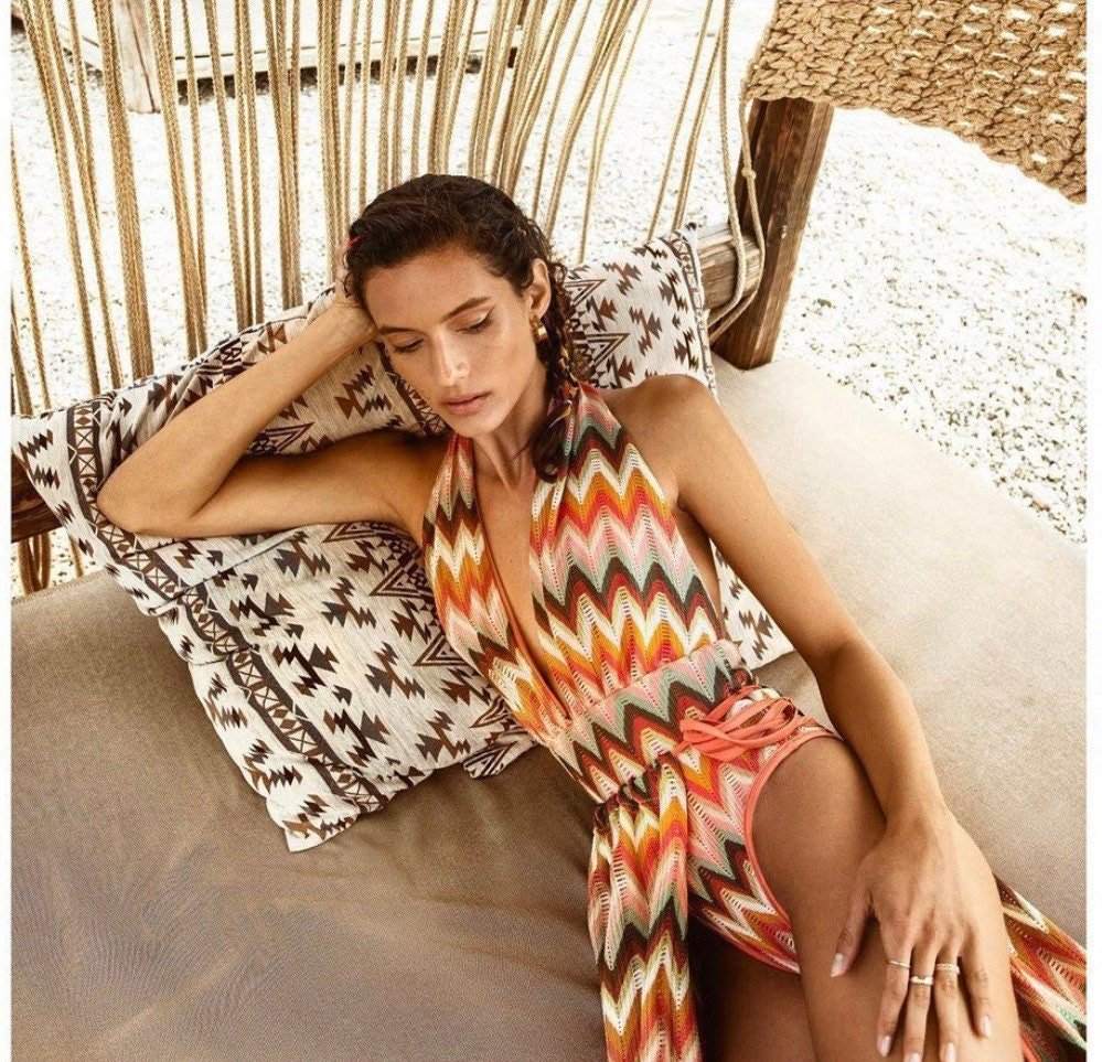 woman wearing luxury autumn chevron zigzag knit jersey fabric halter dress reclining on patterned cushions outdoors