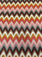 Luxury autumn chevron zigzag knit jersey fabric with warm tones of pink, mustard, black, and white, ideal for elegant autumn attire.