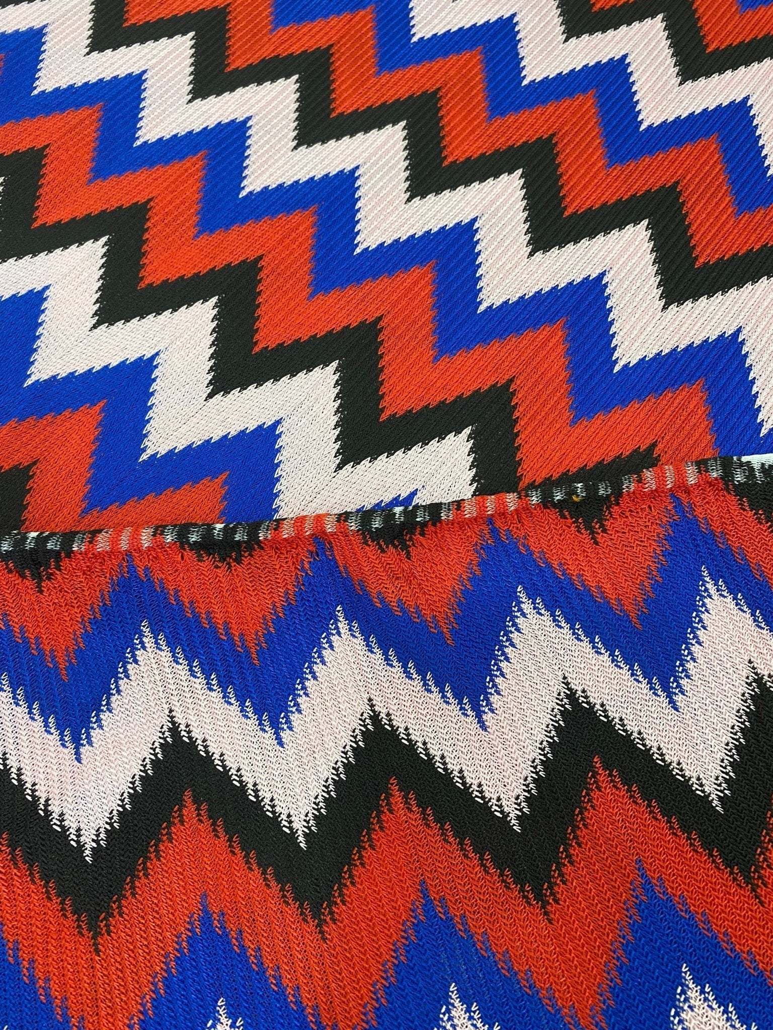 Luxury zigzag knit jersey fabric with vibrant blue, red, black, and pink zigzag pattern, perfect for elegant garments