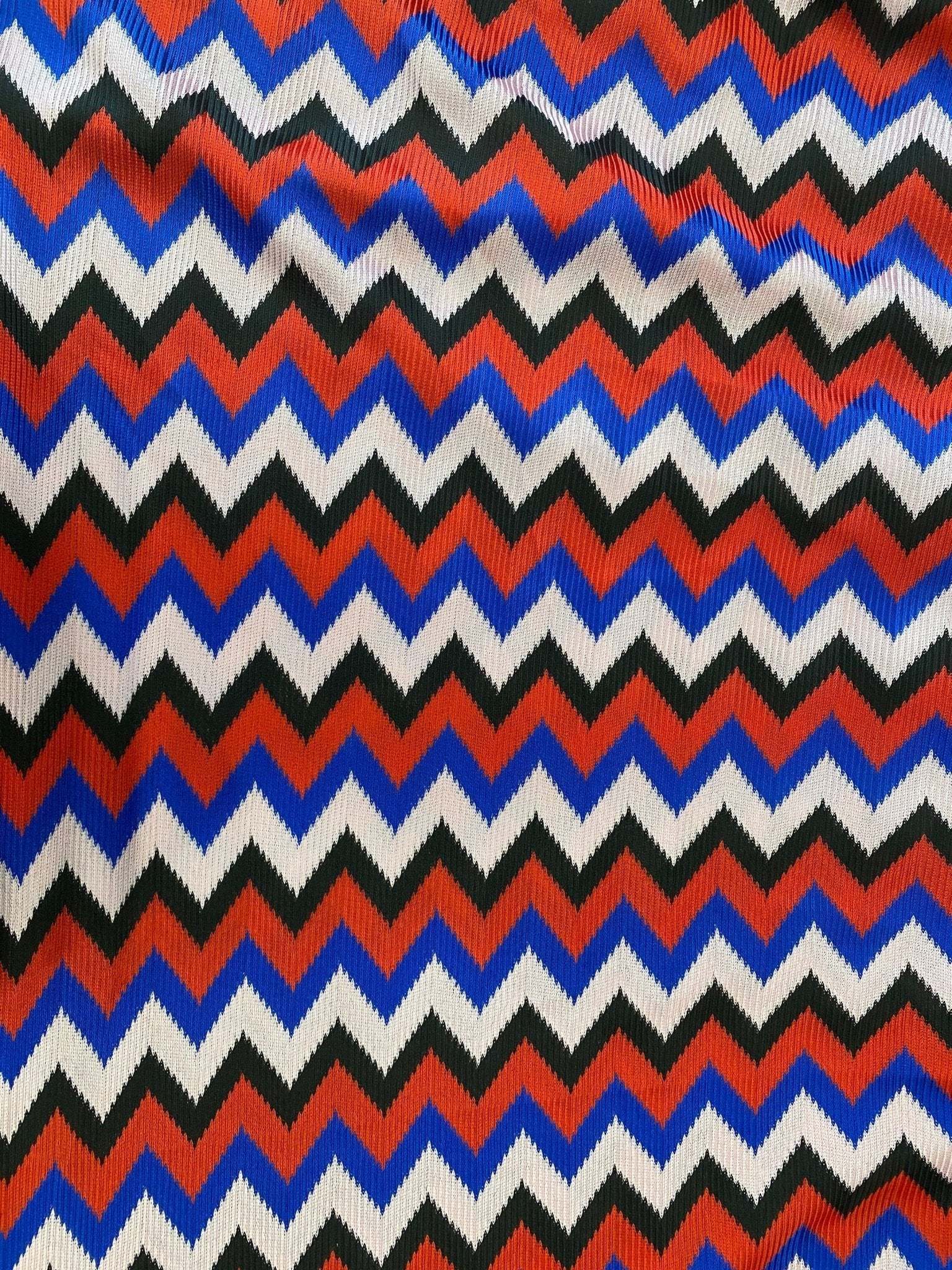 Luxury zigzag knit jersey fabric with blue, red, black, and sugar pink hues in a vibrant chevron pattern